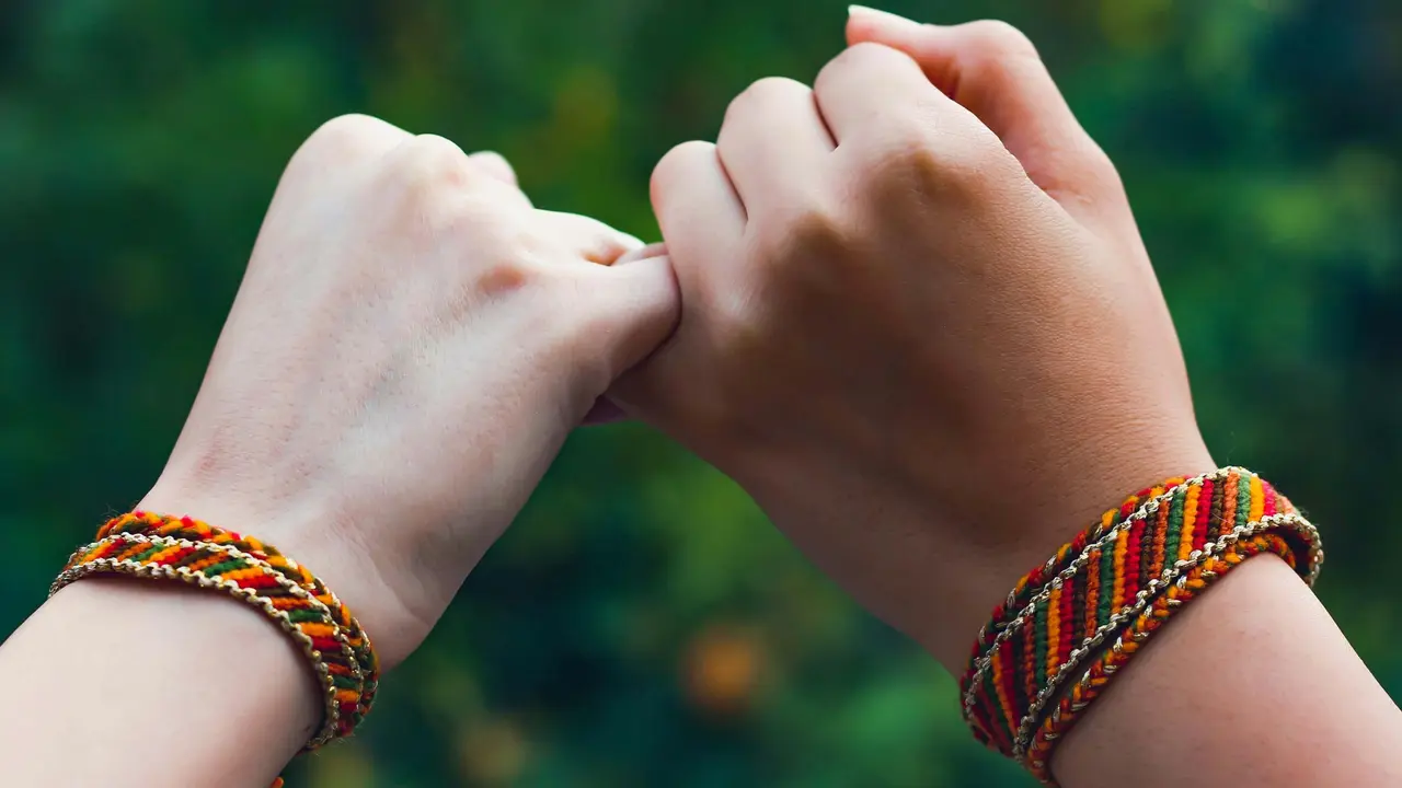Zwei Hände deren kleine Finger ineinander verschränkt sind