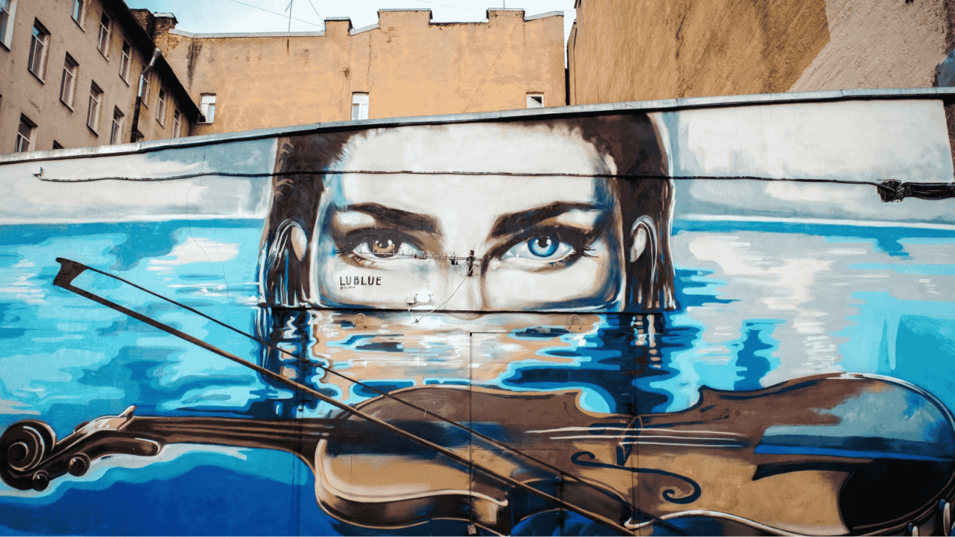 Mural/Street Art, das ein aus dem Wasser auftauchendes Frauengesicht zeigt, vor dem eine Geige auf der Wasseroberfläche schwimmt.