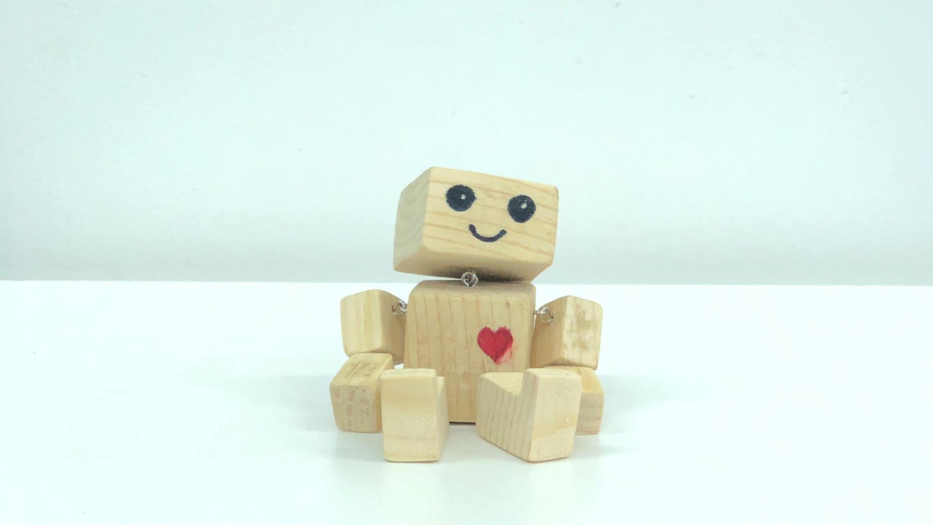 Sitzender Roboter aus Holz mit einem aufgemalten roten Herz